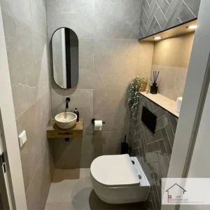 Modern bathroom renovation in Zurich with wall-mounted toilet, stone sink, and decorative lighting.