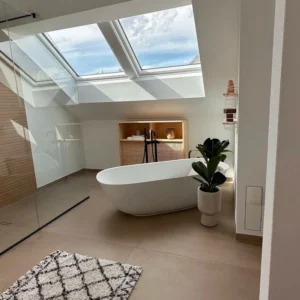Modern bathroom renovation in Zurich with skylight, freestanding bathtub, and custom wood finishes.