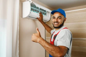 Techniker installiert Klimaanlage in moderner Mietwohnung und zeigt Daumen hoch