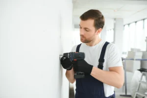 Mann bohrt in Mietwohnung in der Schweiz mit Bohrmaschine
