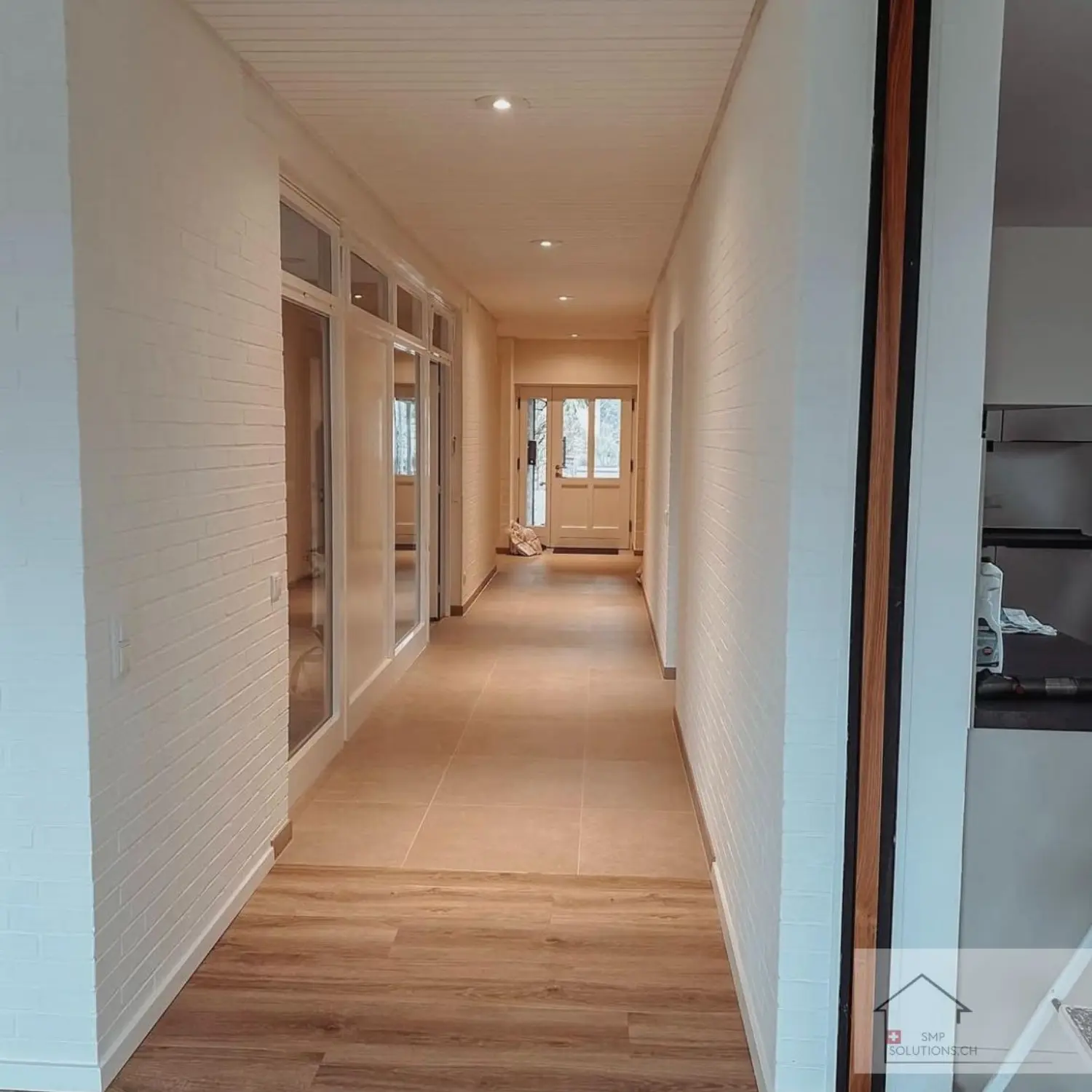 Renovierter Flur in einem Zürcher Haus mit modernem Bodenbelag, frischer Farbe und Einbaubeleuchtung.