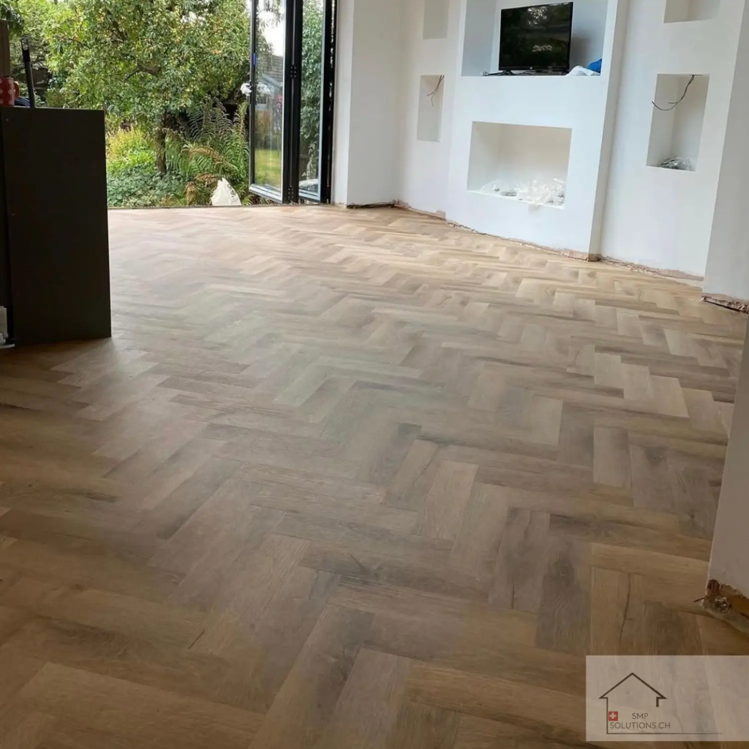 Renoviertes Wohnzimmer in Zürich mit neuem Fischgrätparkett und modernem Interior Design.