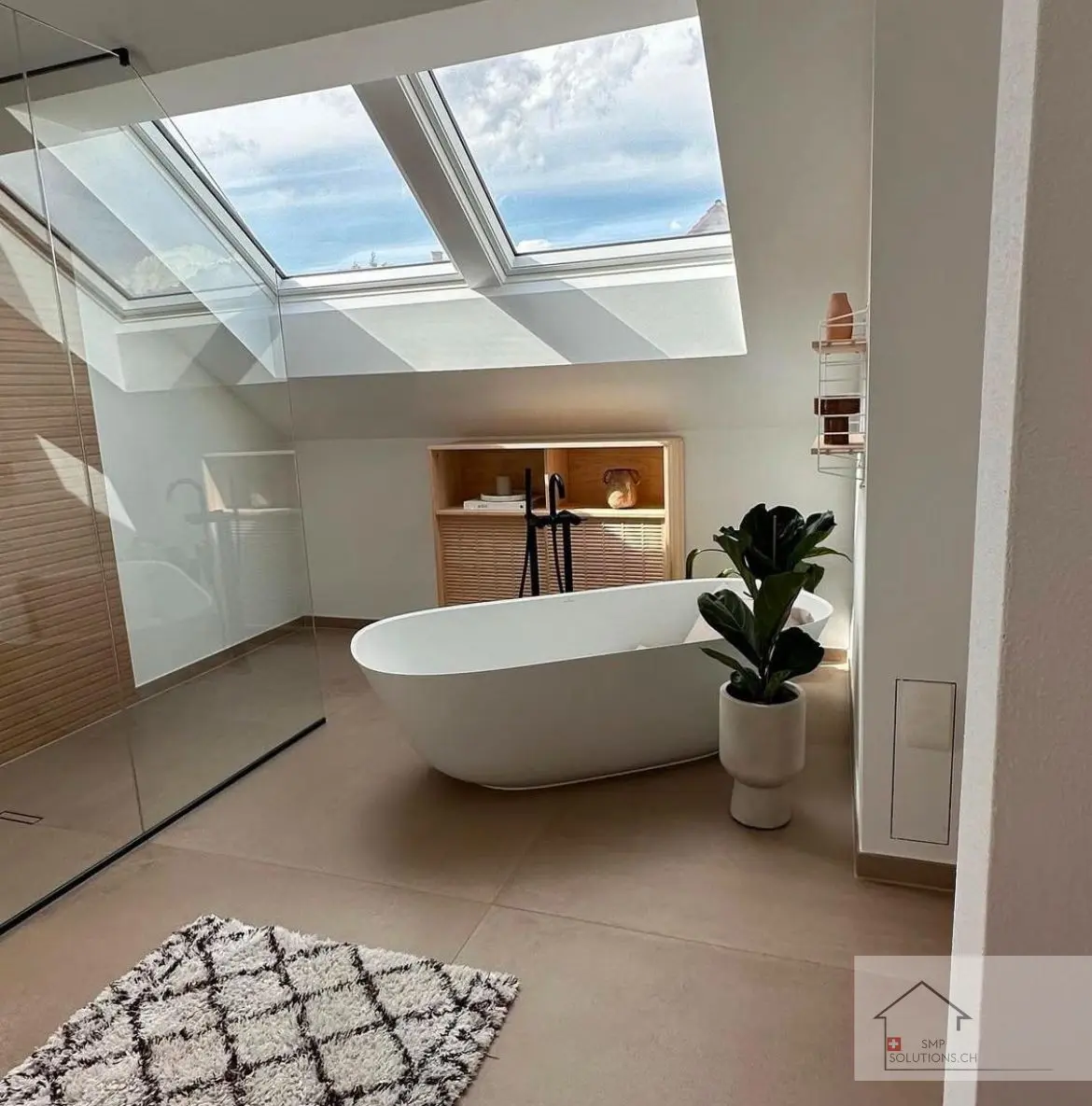 Moderne Badsanierung in Zürich mit Dachfenster, freistehender Badewanne und maßgefertigten Holzelementen.