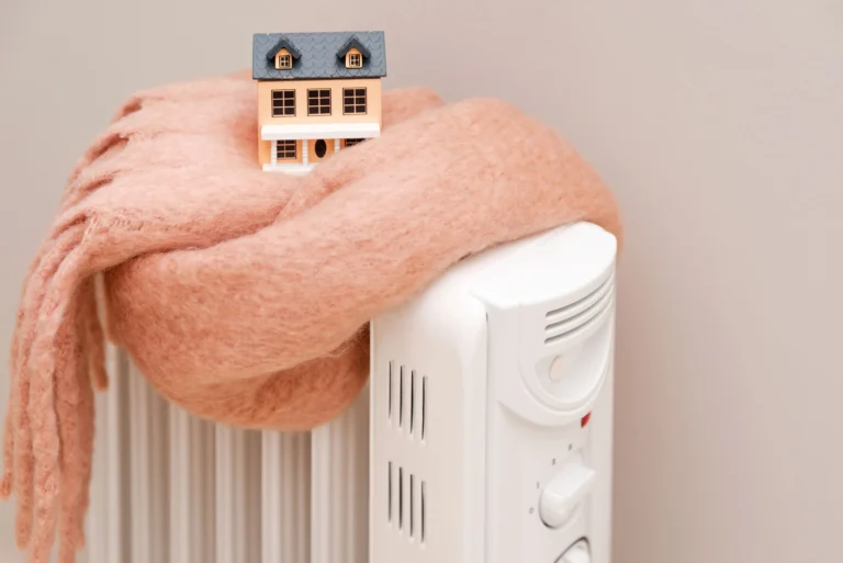 Small model house wrapped in a warm scarf on a radiator, symbolizing winter heating tips for tenants in Zurich