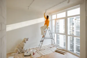 Woman painting a wall in a Zurich apartment with her dog nearby during home renovation.