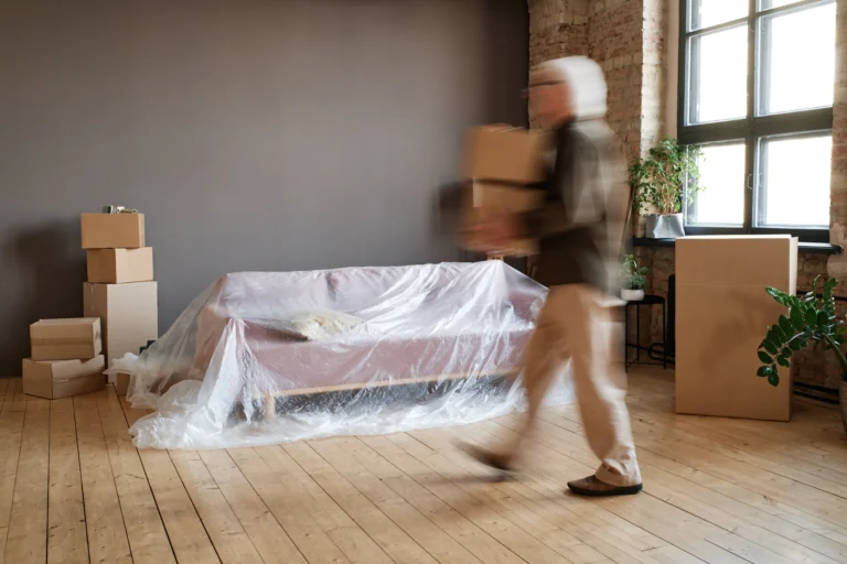 Senior man carrying heavy moving boxes alone during an apartment relocation in Zurich